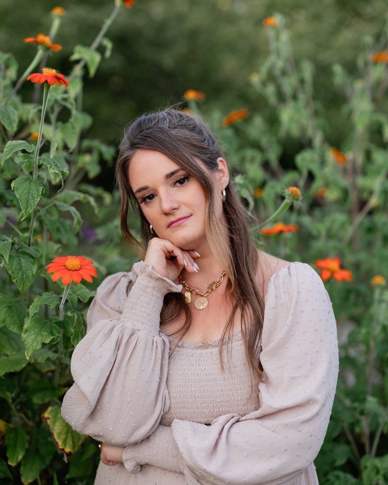 Leah Tarleton, founder and editor of Nourished Sensitive Magazine, among orange wildflowers